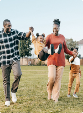 A family of four happily walks through a field